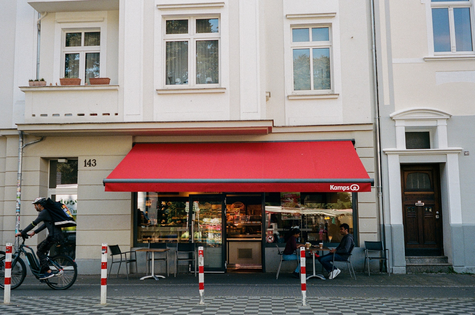 a man riding a bike past a red awning
