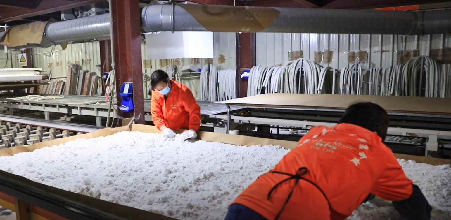 Workers handling raw quartz material on a production line