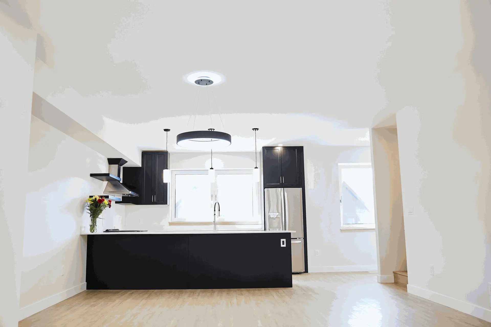 Guangzhou Sourcing Project: Caribou 7-Plex Townhomes Kitchen Design Modern kitchen in a spacious open-concept living area featuring black cabinetry, stainless steel appliances, and a large island with a countertop.